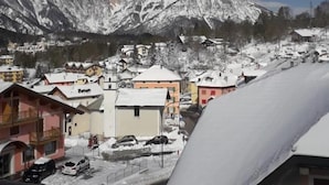 Un pueblo montañoso nevado con edificios y un cielo azul despejado.