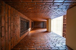 A narrow brick corridor with a vaulted ceiling and a view of a wooden door at the end. - Traditional Stay (Lalitpur)