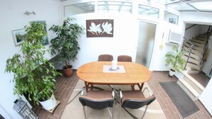 A spacious indoor area with a round wooden table and four chairs, surrounded by potted plants and a staircase. - Haus Budinger Ferienwohnung Appartements (Alf)