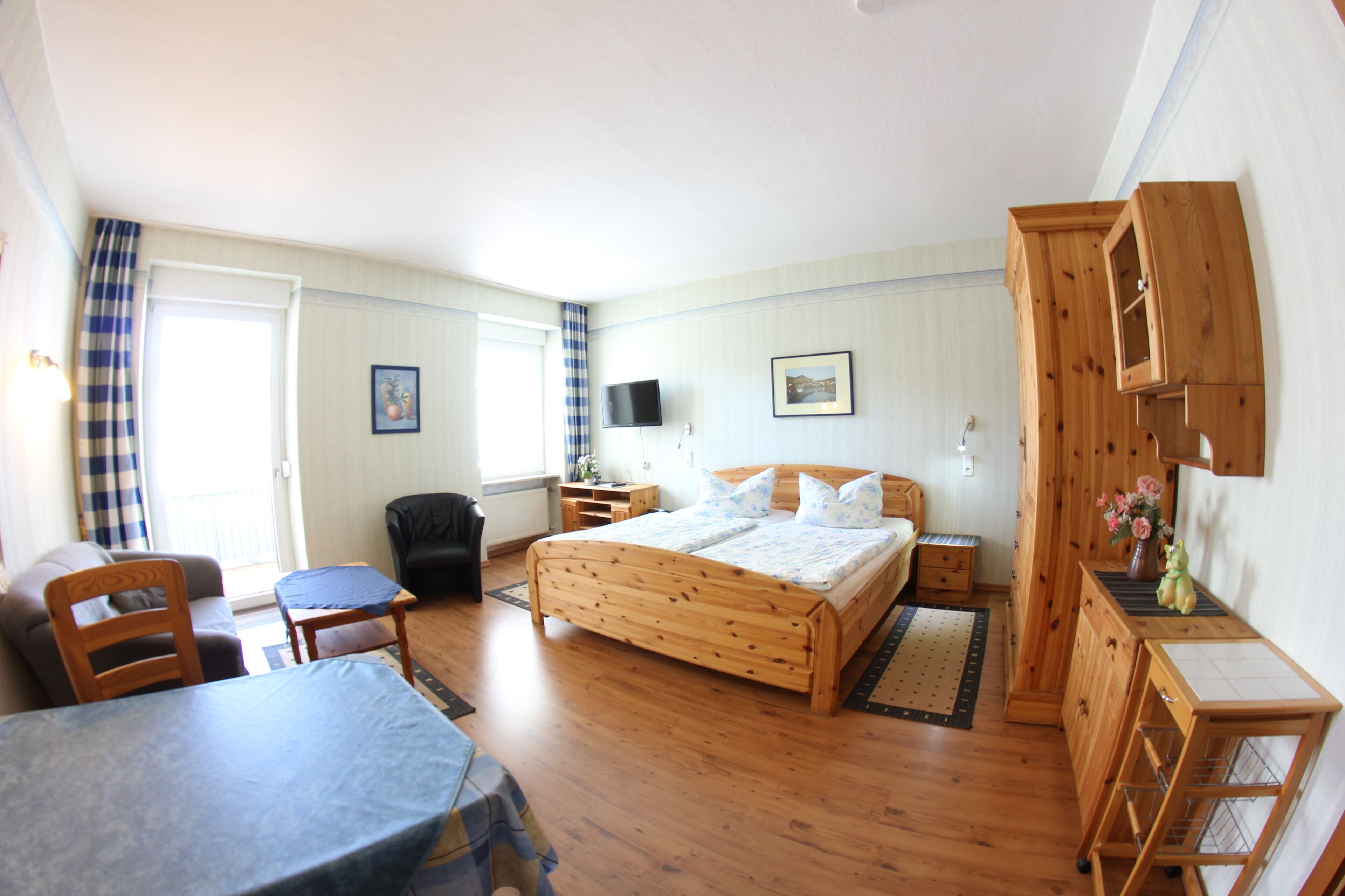 A bedroom with a wooden bed, a desk, a chair, and a television.