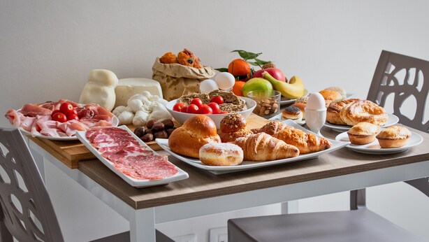 A table with various food items including meats, cheeses, fruits, and pastries. - B&B Gianmarti Suite (Lecce)