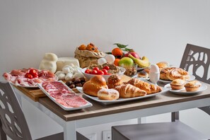 A table with various food items including meats, cheeses, fruits, and pastries. - B&B Gianmarti Suite (Lecce)