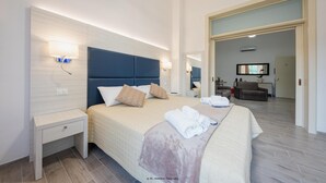 A modern hotel room with a large bed, bedside tables, a flat-screen TV, and a bathroom visible through an open door. - B&B Gianmarti Suite (Lecce)