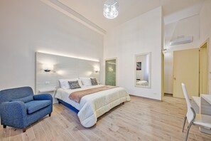 A modern bedroom with a bed, a blue armchair, a bedside table, and a large mirror. - B&B Gianmarti Suite (Lecce)