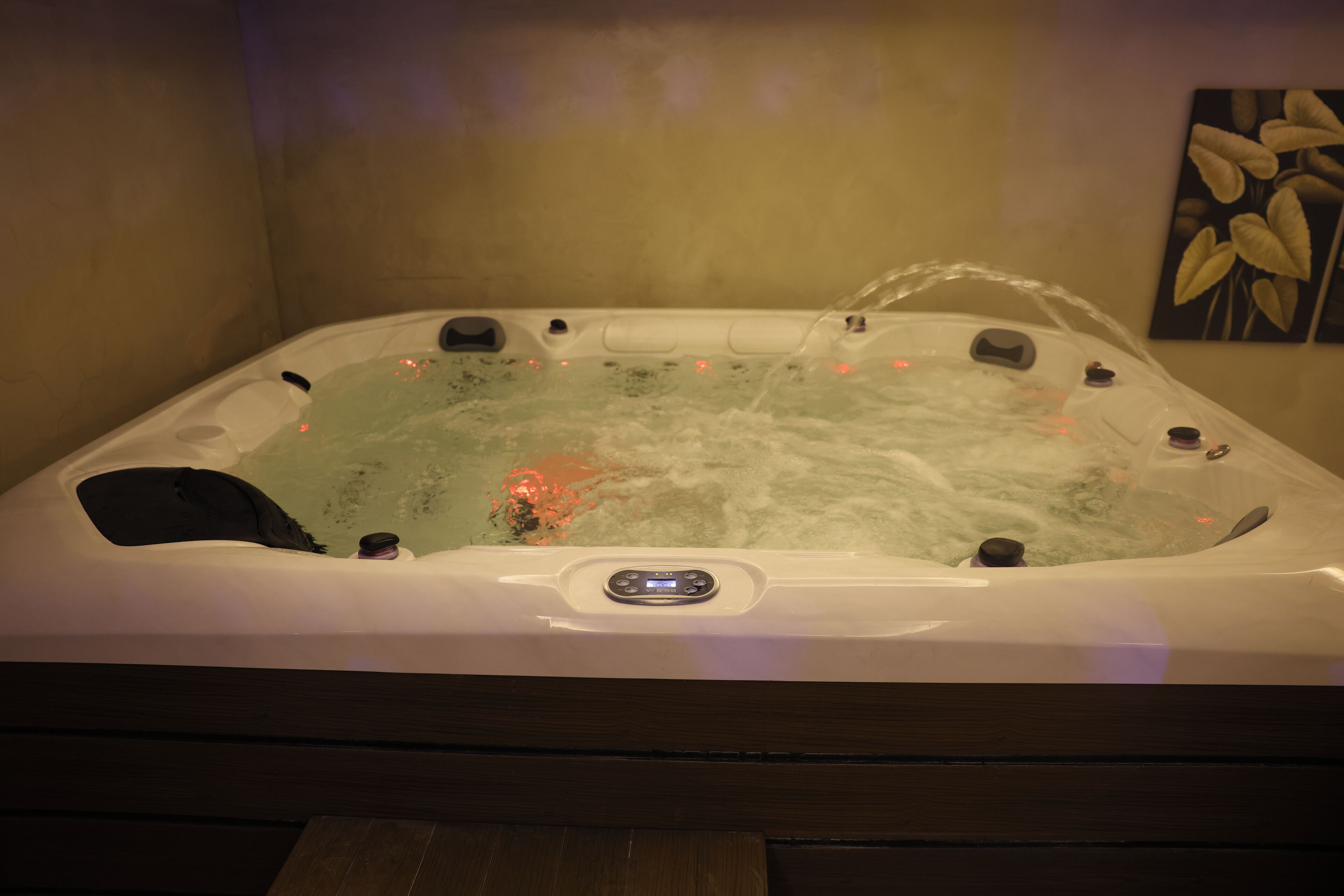 Un jacuzzi con panel de control, rodeado por un banco de madera.