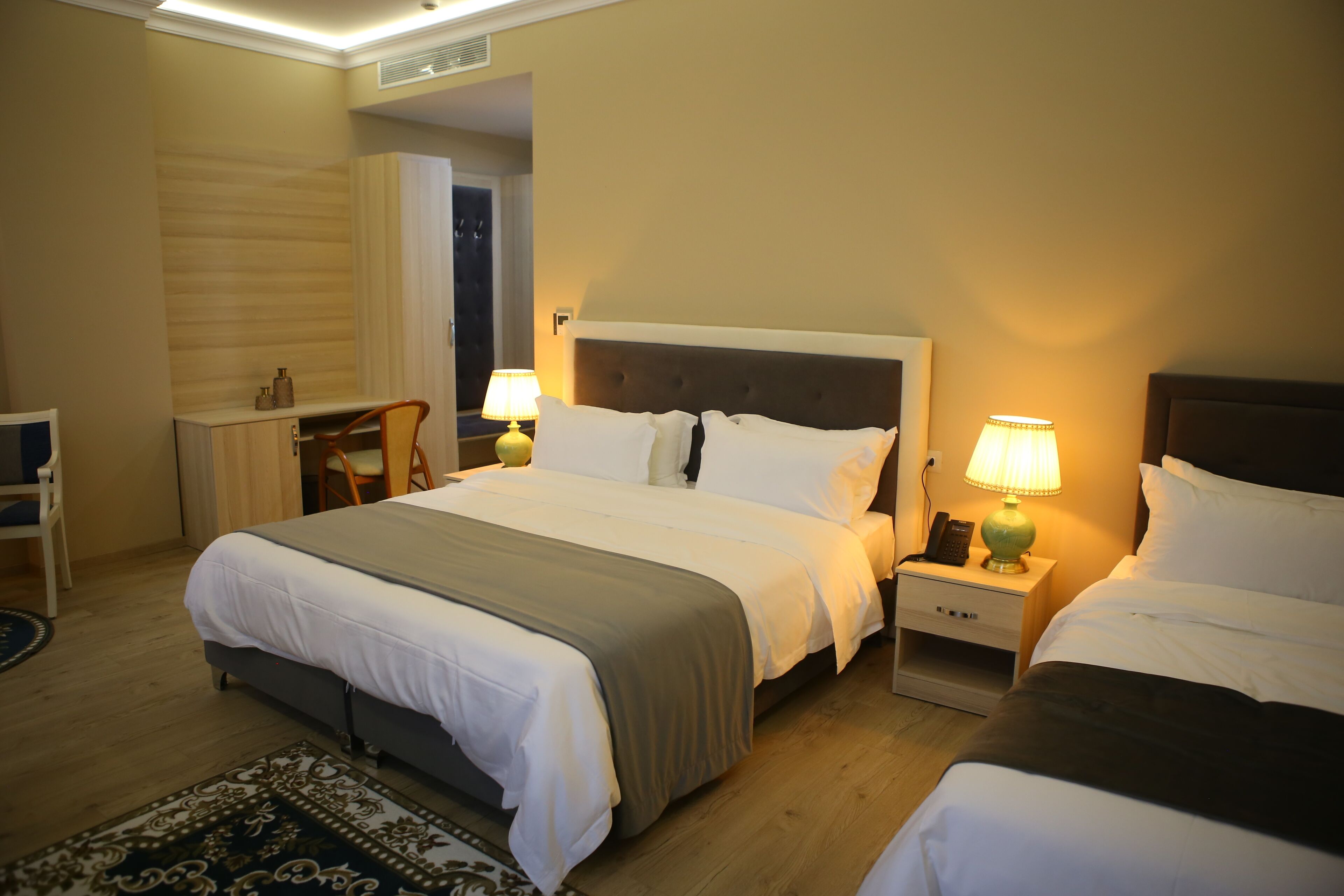 Habitación de hotel con una cama grande, dos mesitas de noche con lámparas, un escritorio y una silla.