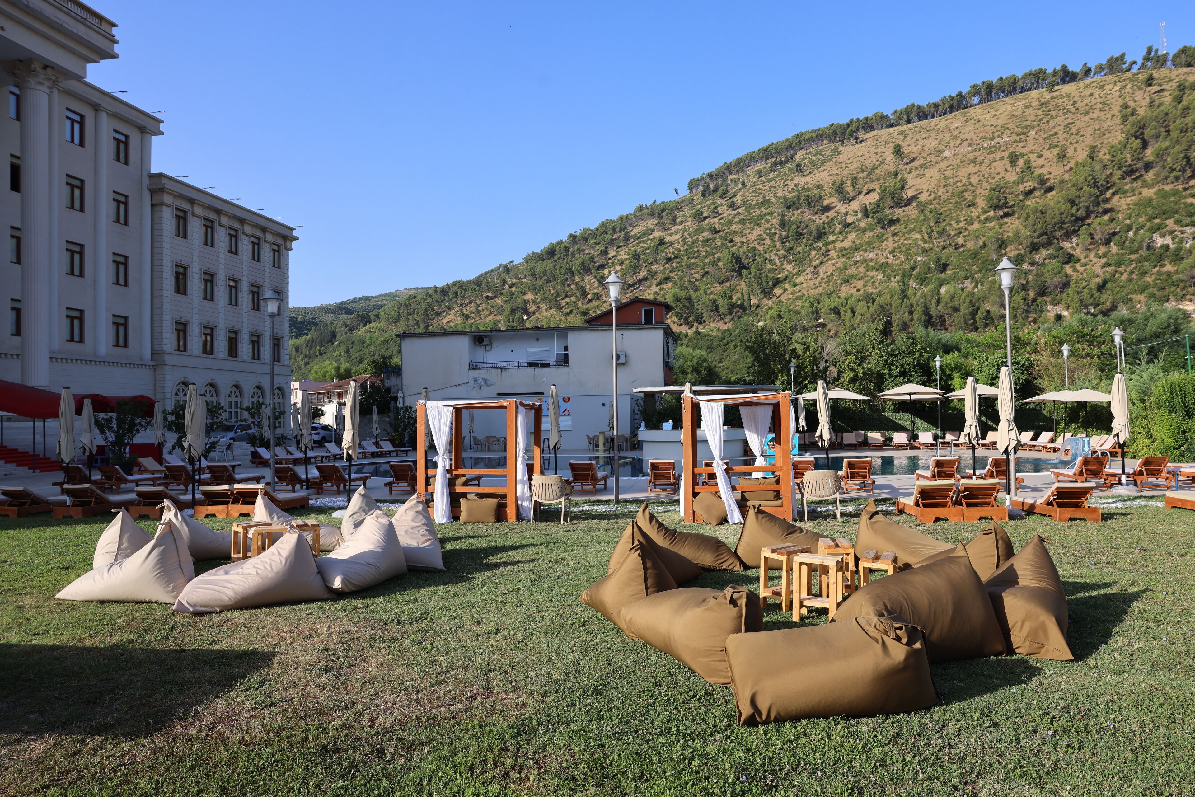 Ein Hotel mit Außenbereichen zum Sitzen, darunter Liegestühle und Stühle, in der Nähe eines Pools.