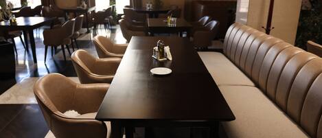 A dining area with a long table, several chairs, and a sofa.