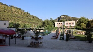 Un resort con asientos al aire libre, piscina y vista a una colina.