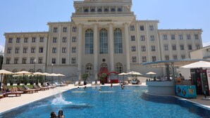 Un gran hotel con piscina central, varias zonas de descanso y una estructura de cúpula destacada.