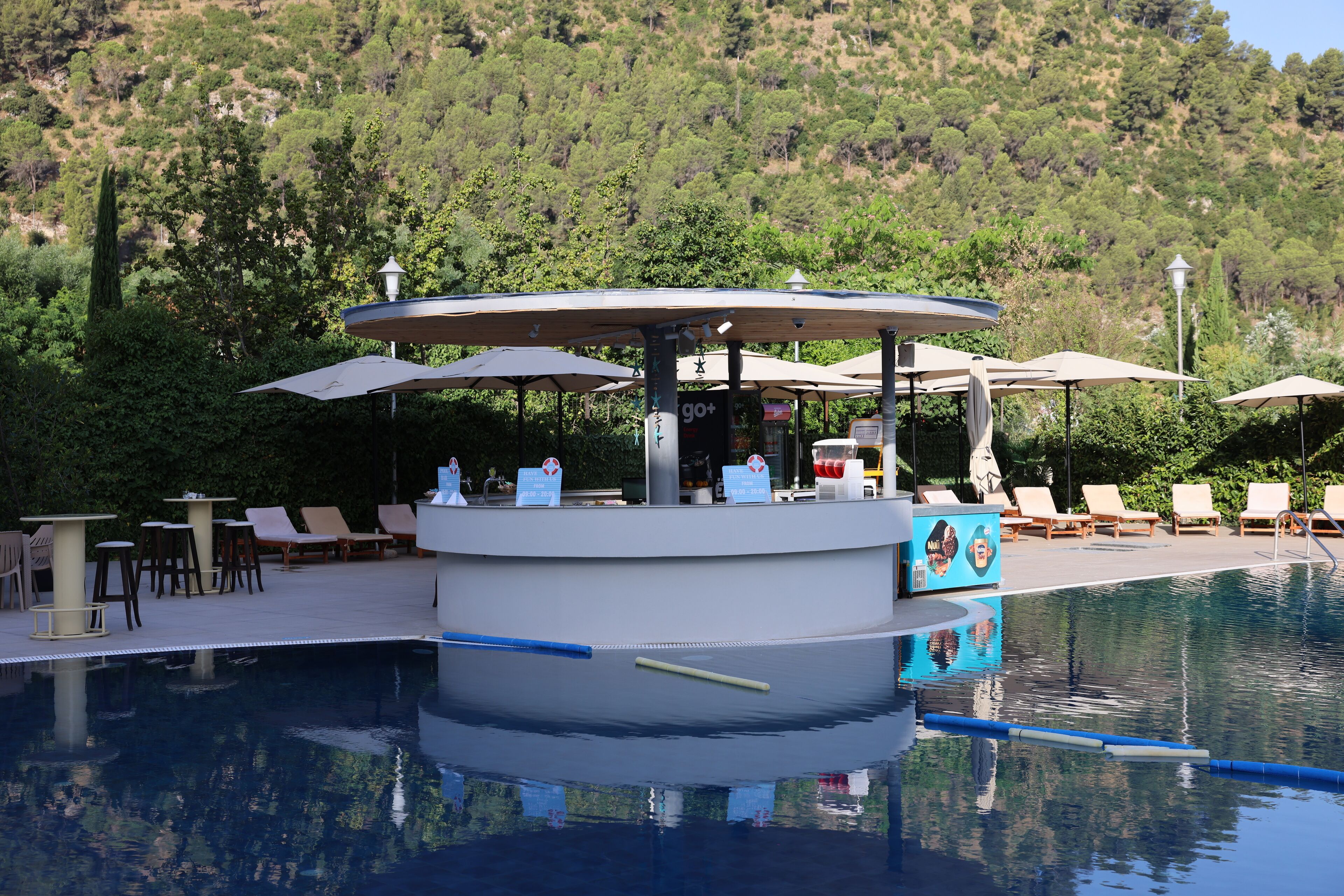 Un área de piscina con bar, sillones y sombrillas.
