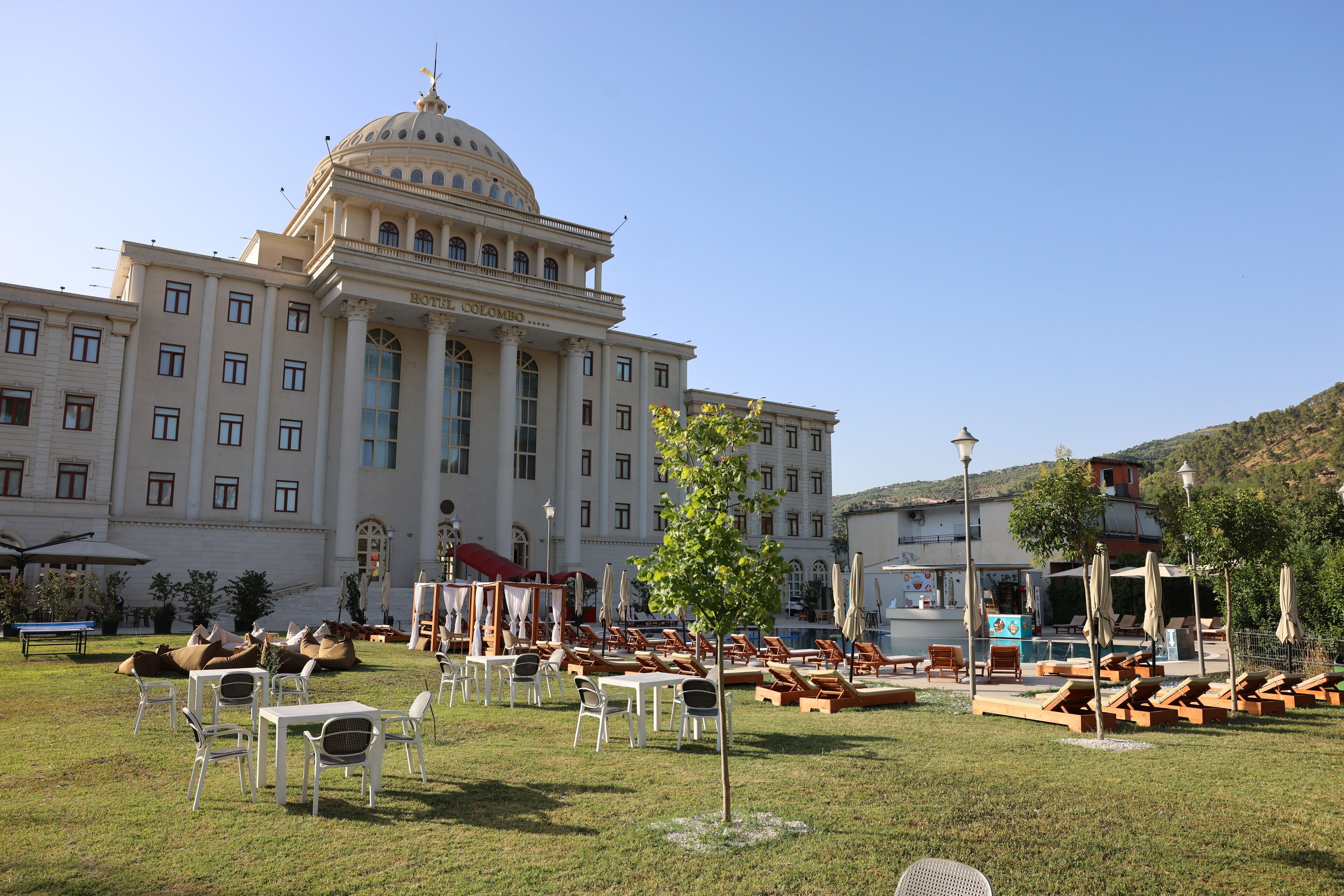 Ein Hotel mit einer großen Kuppel und klassischer Architektur, Außenbereich mit Sitzgelegenheiten und einem Pool.