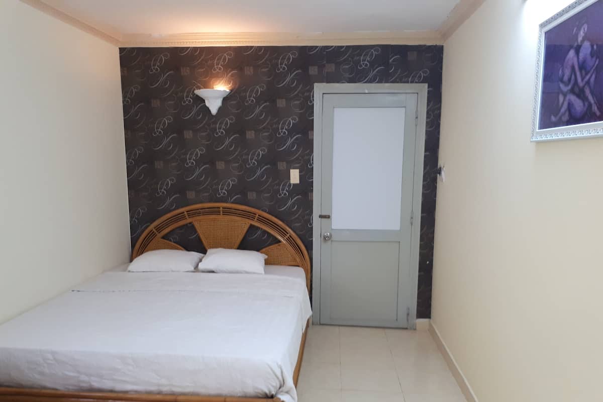 Un dormitorio con una cama, una puerta y una lámpara fijada a la pared.