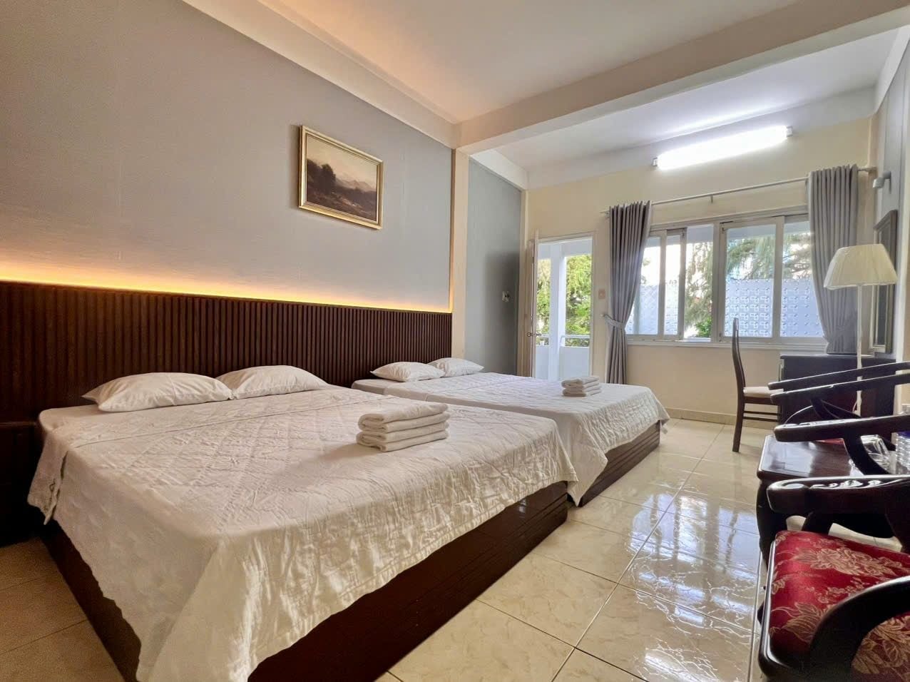 A hotel room with two beds, a desk, and a chair.