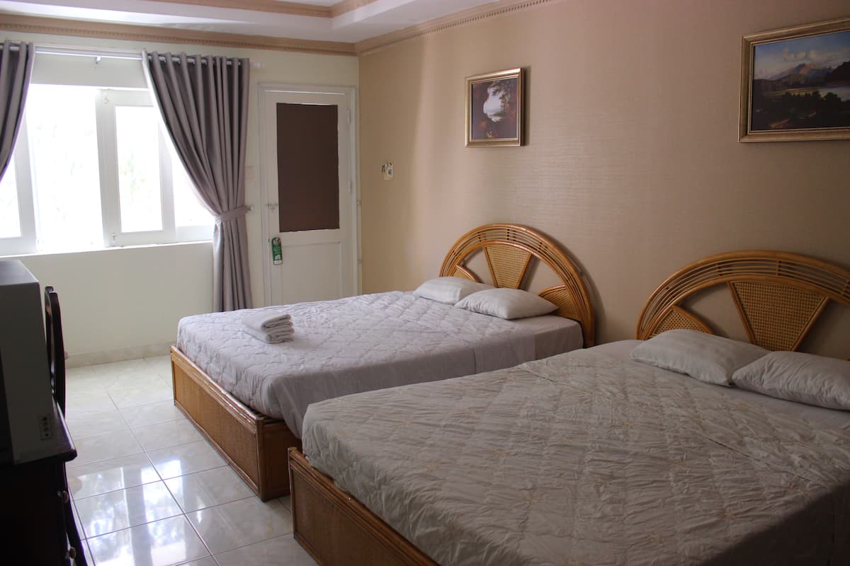 Habitación de hotel con dos camas individuales, un televisor y una puerta con cortinas.