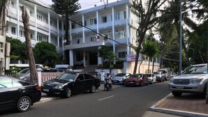 A multi-story building with a prominent entrance, several flags, and a sign for 'LAM S HOTEL'.