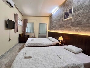 Une chambre d’hôtel avec deux lits, une télévision, un tableau accroché au mur et une tête de lit en bois.