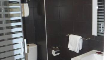 Un baño moderno con inodoro, lavabo y cabina de ducha de vidrio.
