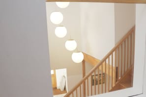 A staircase with wooden railings and a series of spherical pendant lights.