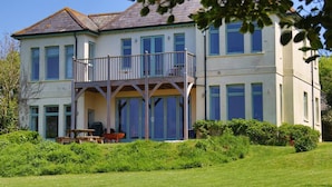 Ein zweistöckiges Haus mit Balkon, Rasen und Garten.