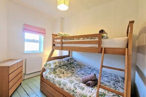 Habitación con literas, una ventana, un radiador y un aparador de madera.