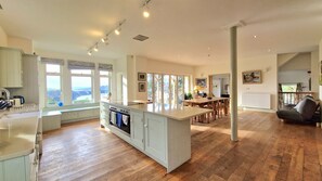 A spacious kitchen with a large island, wooden flooring, and a view of the outdoors.