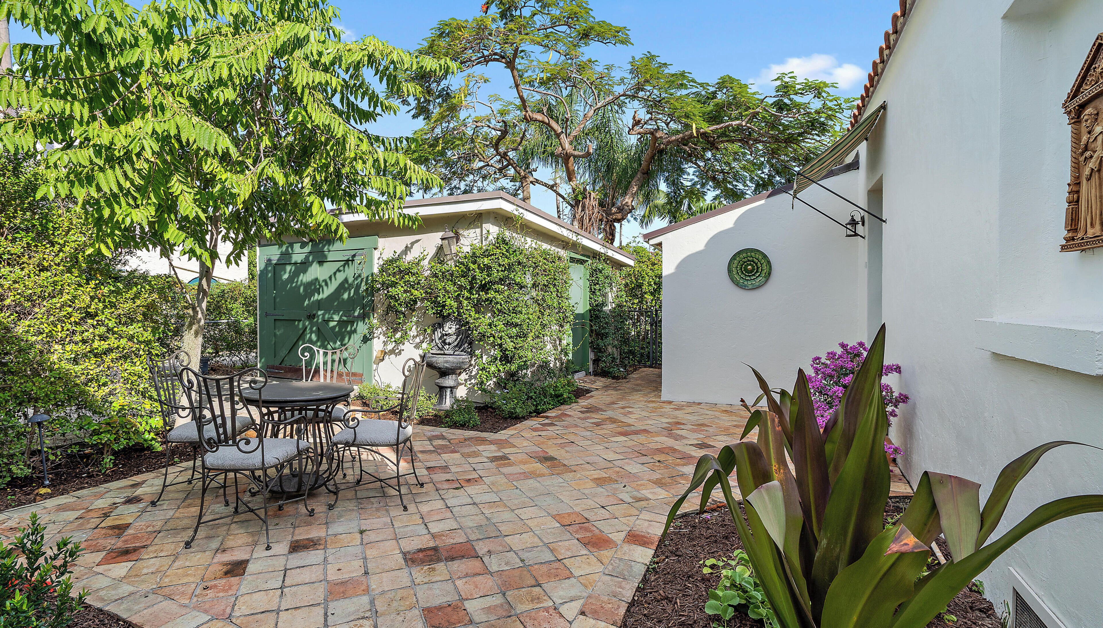 Un patio con una terraza, una mesa y sillas, y un árbol.