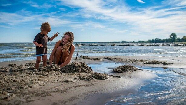 A beach scene with two people near the water's edge, engaging in an activity. - traumHaff Protected monument Malchen's yard, sauna, open fireplace, fenced meadow (Ahlbeck OT Gegensee)