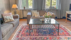 A living room with a sofa, a coffee table, a lamp, and a TV. - traumHaff Protected monument Malchen's yard, sauna, open fireplace, fenced meadow (Ahlbeck OT Gegensee)
