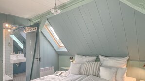 A bedroom with a sloped ceiling, a skylight, a bed with white bedding, and a small bedside table. - traumHaff Protected monument Malchen's yard, sauna, open fireplace, fenced meadow (Ahlbeck OT Gegensee)
