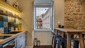 Cocina compacta con vista por la ventana, electrodomésticos integrados y pared de piedra.