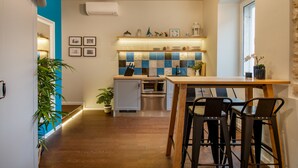 Una cocina moderna con una mesa de madera y taburetes, un salpicadero de azulejos y una lámpara colgante.