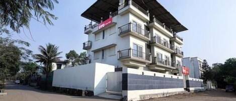 A multi-story building with balconies, a flat roof, and a gated entrance.