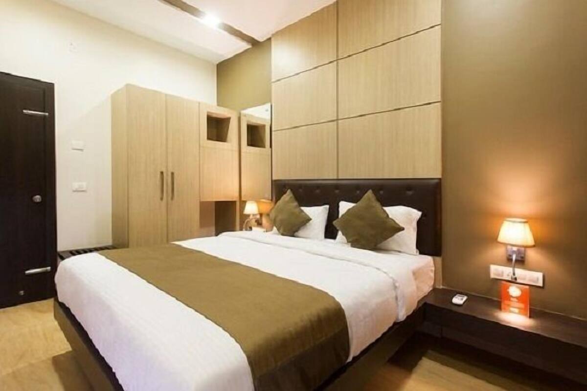 A hotel room with a bed, bedside lamps, a wardrobe, and a nightstand.