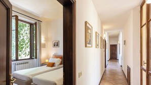 A hallway with two beds, a radiator, and framed pictures on the wall. - Rental In Rome Rosselli Palace Apartment 2 (Florence)