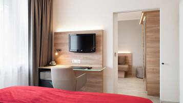 Een moderne hotelkamer met een bed, een bureau met een computer, een flatscreen-televisie en een inloopkast.