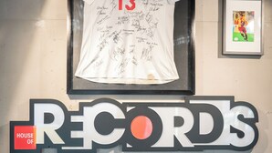 Una parete con una maglia incorniciata, una foto incorniciata e un'insegna con la scritta 'RECORDS'.