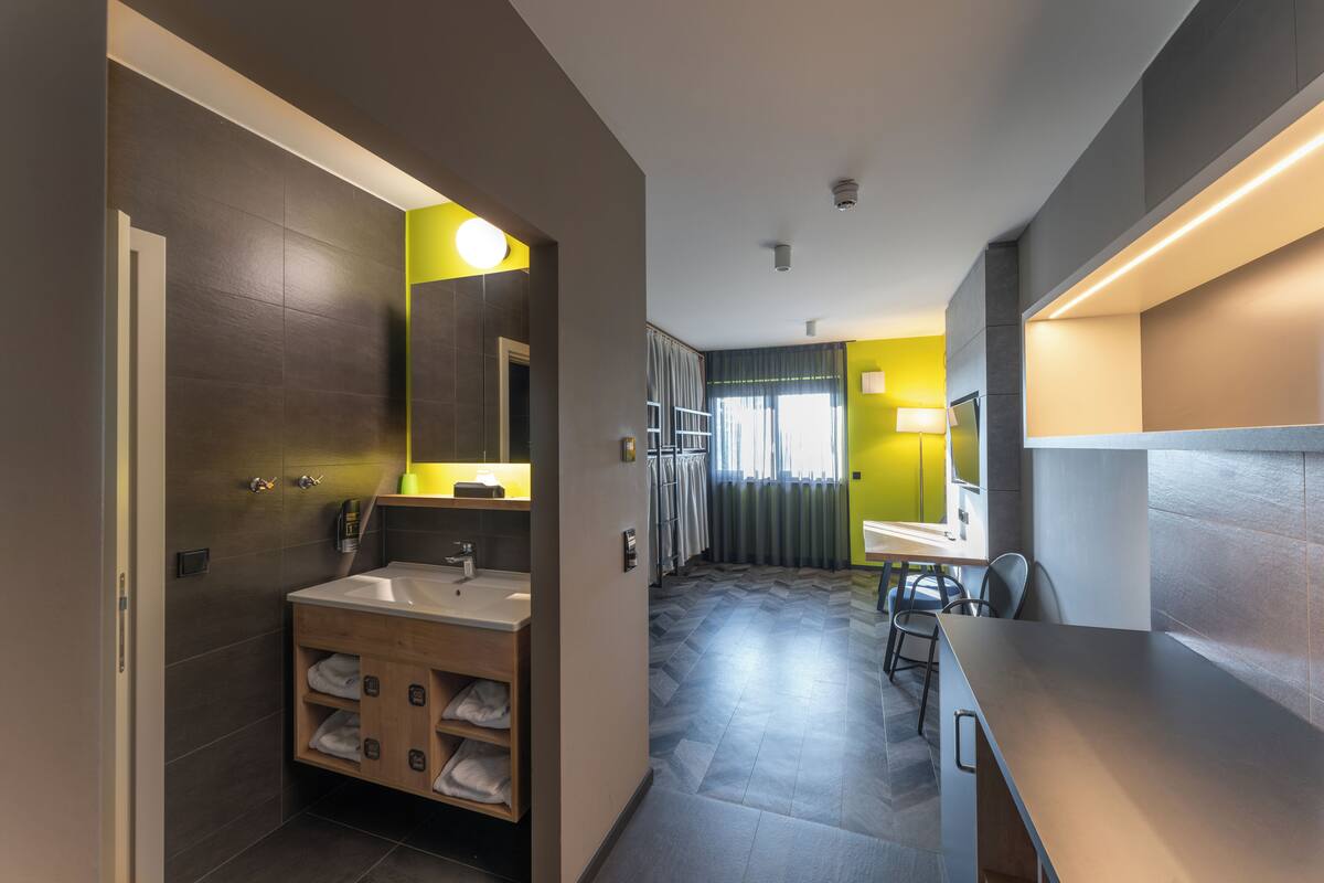 A modern bathroom with a sink, mirror, and towel storage.