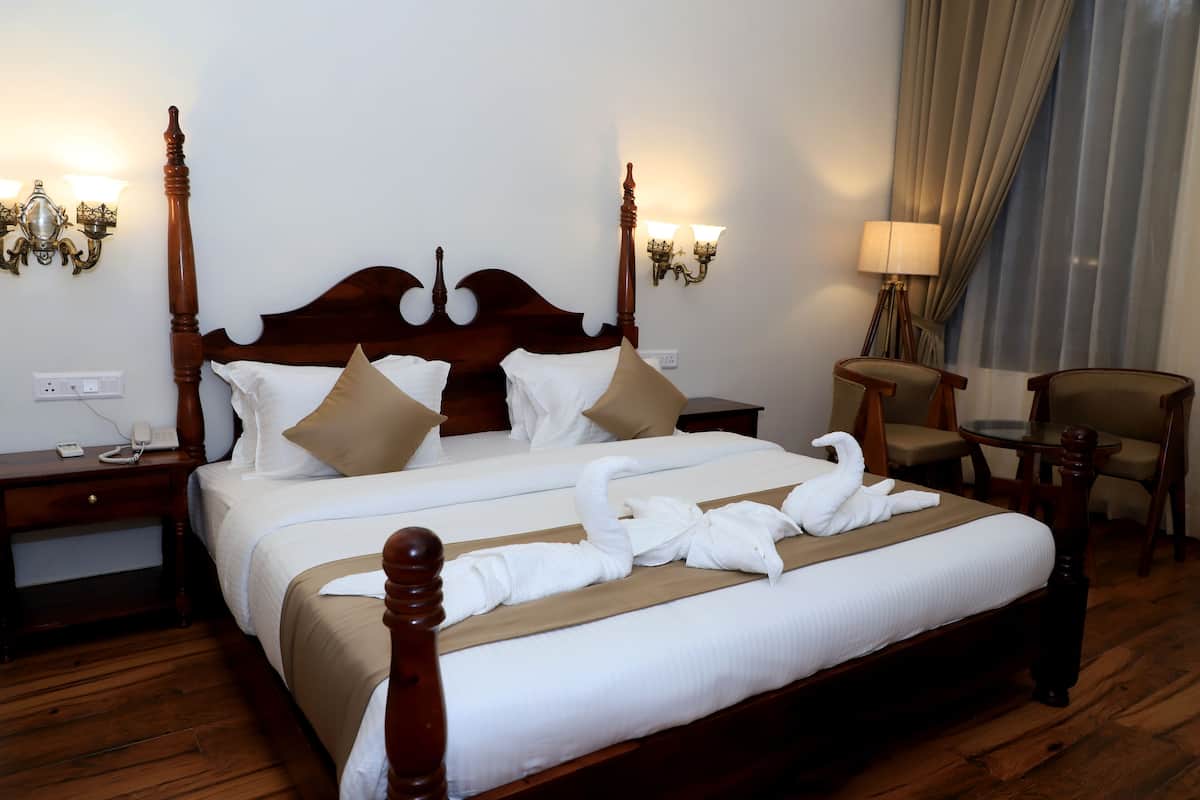 A neatly made bed with a wooden headboard, two bedside tables, a lamp, and a chair.