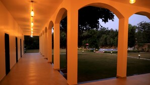 A corridor with arches and a view of a lawn area. - Aroma Resort Pushkar (Pushkar)