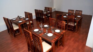 A dining area with wooden tables and chairs, arranged in a U-shape. - Aroma Resort Pushkar (Pushkar)