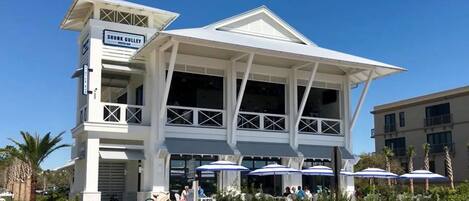 A building with a sign reading "SHUNK GULLEY" and a covered outdoor seating area with umbrellas.