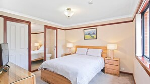 Una camera da letto con un letto di legno, due comodini con lampade, uno specchio e una finestra con vista.