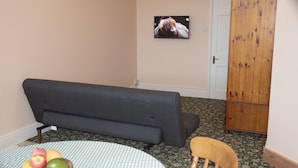 A room with a sofa, a wooden chair, a table with fruit, and a framed picture on the wall. - The Orangery Apartment (Bristol)