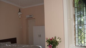 A bedroom with a bed, a vase of flowers, a window with bars, and a white door. - The Orangery Apartment (Bristol)