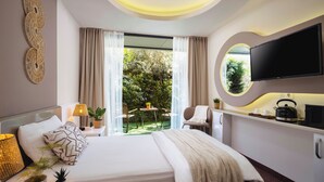 A modern hotel room with a bed, bedside table, lamp, potted plants, and a TV. - IS Hotel (Antalya)