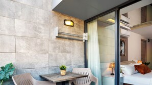 A modern hotel room with a glass door leading to a balcony, a small table with chairs, and a potted plant. - IS Hotel (Antalya)