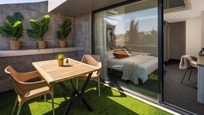 A modern room with a bed, a dining area with a table and chairs, and a balcony with potted plants. - IS Hotel (Antalya)