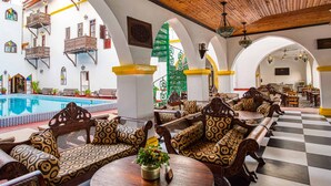 Un hall de hotel con piscina, muebles de madera y suelo a cuadros.
