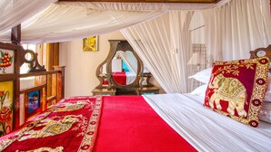 Una cama con una colcha rojo y blanco, un dosel y un cojín decorativo.